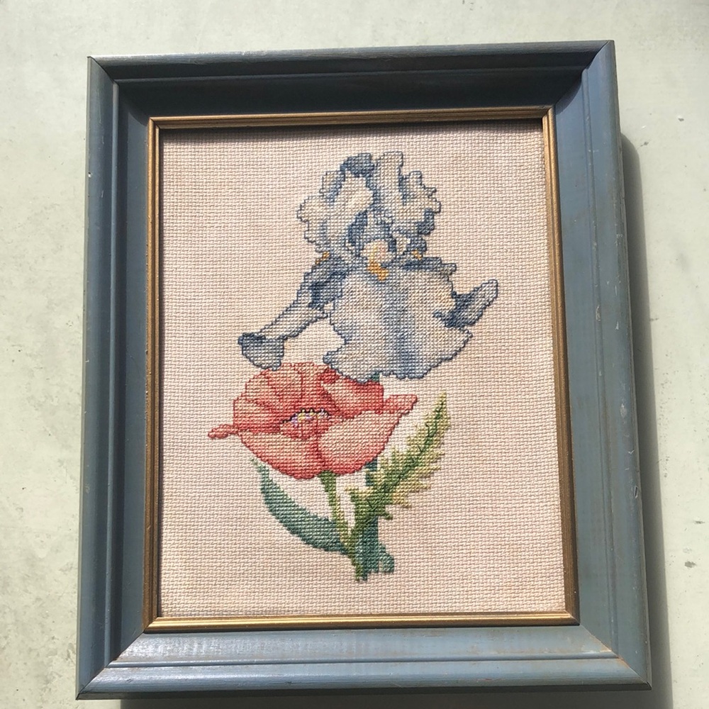 Cross stitch of  a blue iris&orange poppy /blue wooden frame/cream background